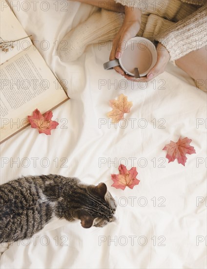 Woman with coffee near cat book