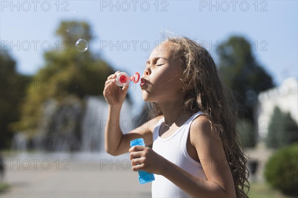 Side view girl blowing bubbles