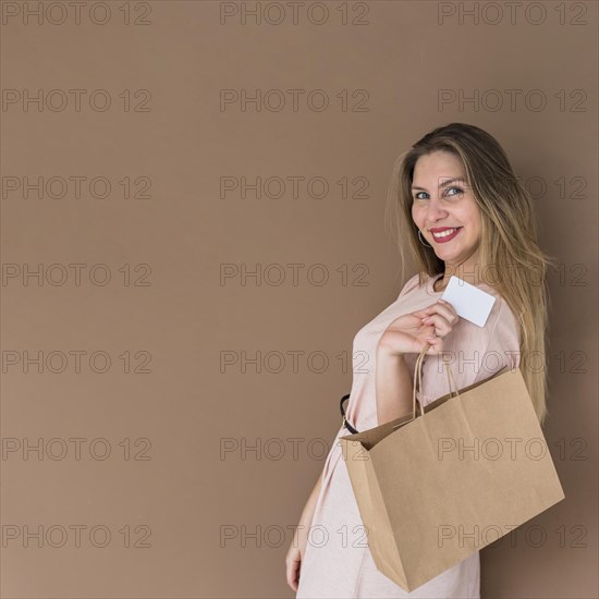 Happy woman standing with shopping bag credit card