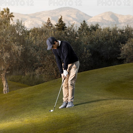 Side view man playing grassy golf field