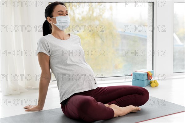 Pregnant woman with medical mask relaxing