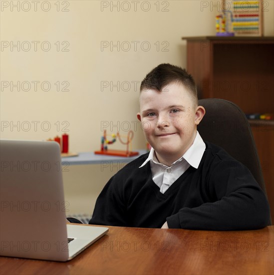 Boy with down syndrome posing with laptop