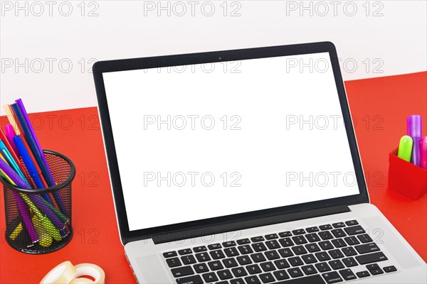 Close up modern laptop with blank white screen red table