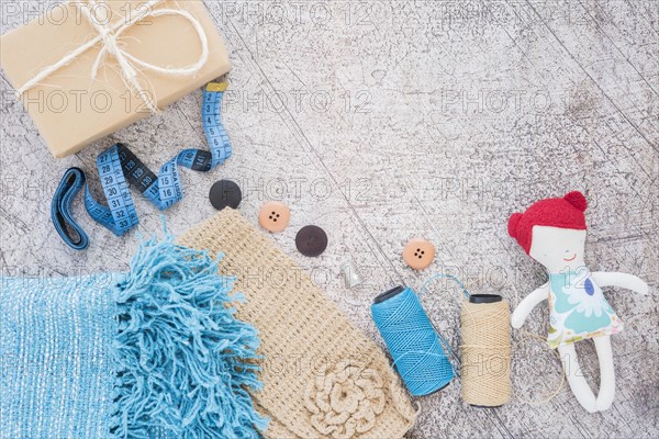 Wrapped gift box measuring tape buttons spool doll textured backdrop