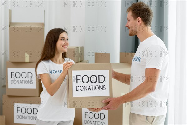 Side view volunteers handling boxes with food donations