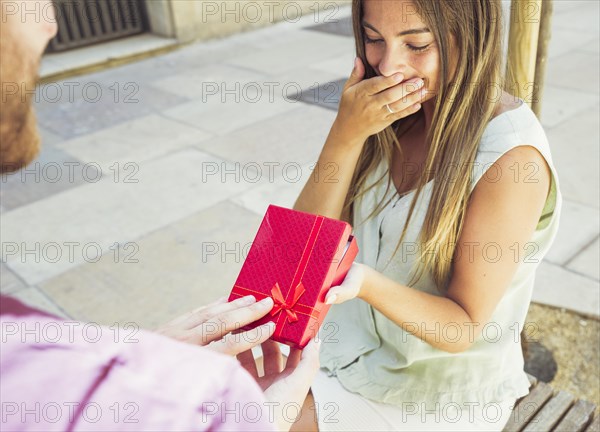Surprised young woman receiving gift from her boyfriend
