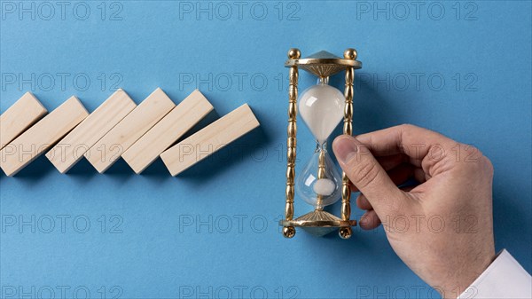 Top view domino pieces with businessman holding hourglass