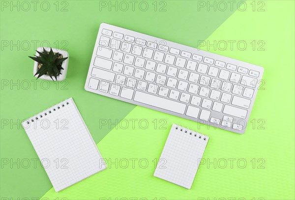 Top view stationery arrangement green background with empty notepads