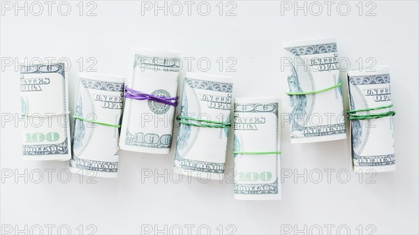 Rolled up one hundred us dollar bills tied with rubber white background