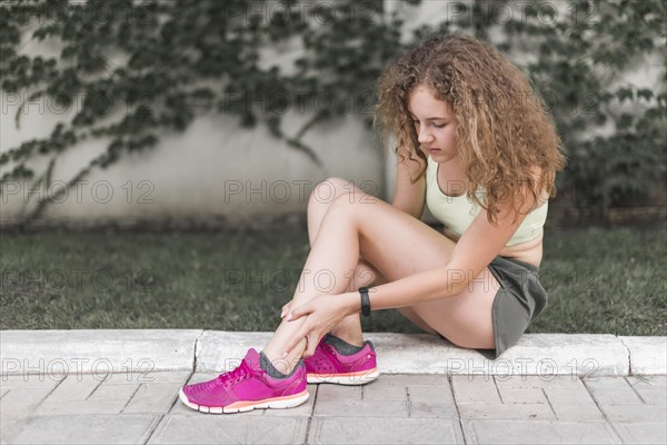 Woman sitting park looking injured ankle