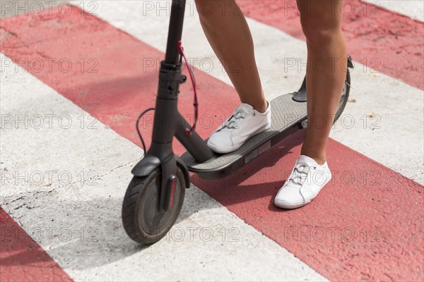 Woman with tennis shoes riding scooter