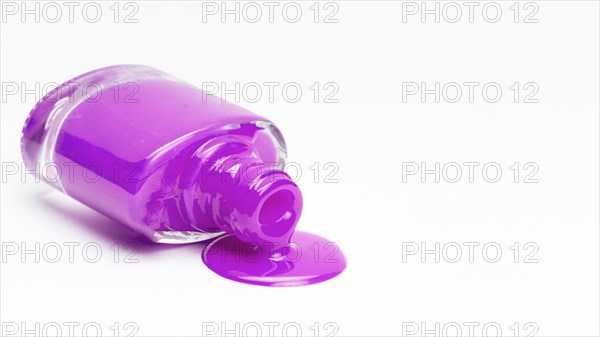 Fallen pink nail polish bottle isolated white surface