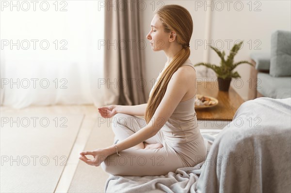 Side view young woman meditating home