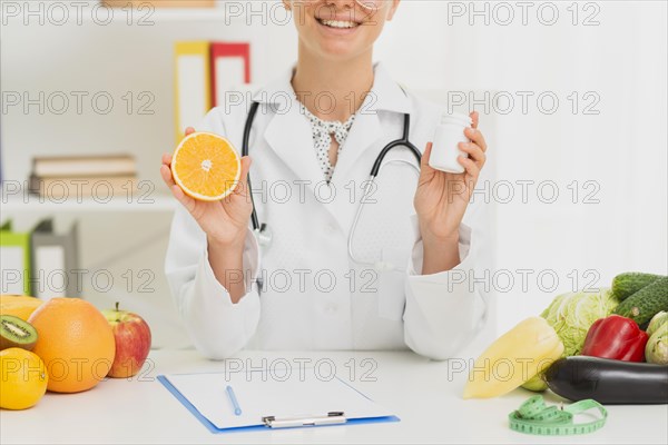 Close up doctor holding up half orange