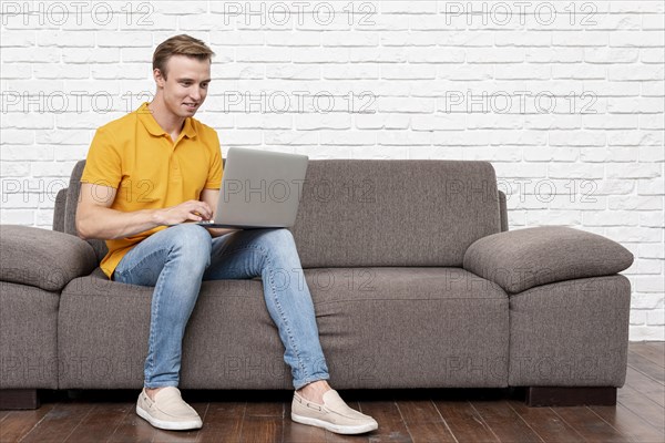 Front view man sitting while checking laptop