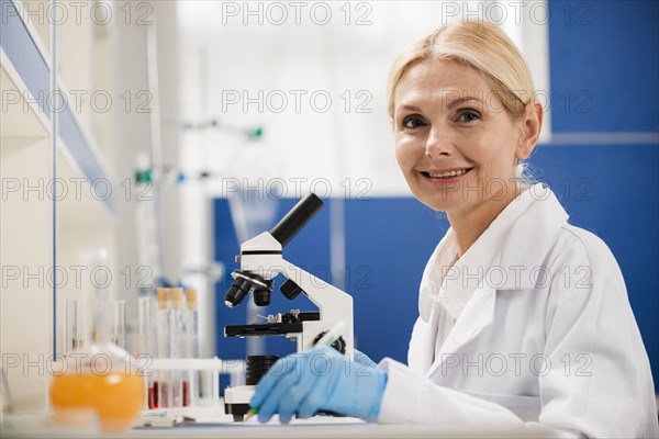 Side view female scientist posing lab with microscope surgical gloves