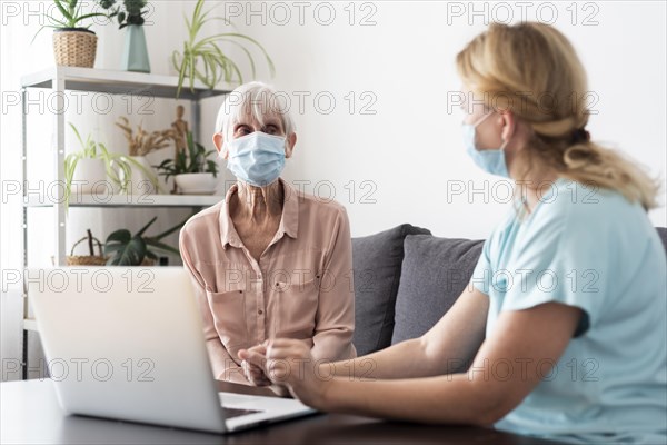 Female nurse older woman conversing laptop nursing home