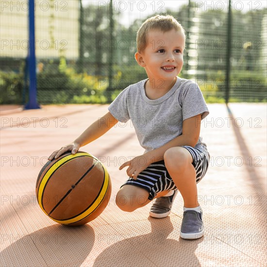 Happy boy playing basketball outdoors