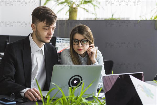 Two young businesspeople using laptop workplace