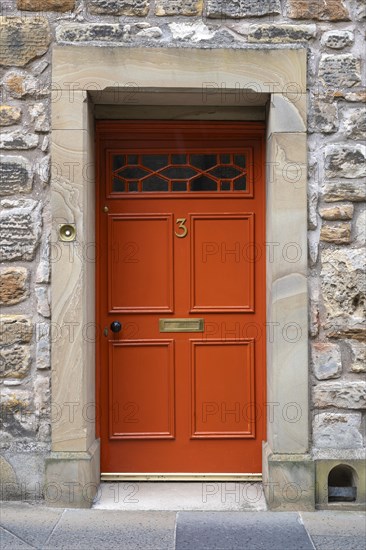 Red front door on an old stone house
