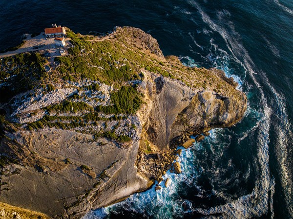 Aerial drone view of Cabo Espichel cape Espichel on Atlantic ocean at sunset with ruins