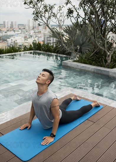 Man doing yoga by pool