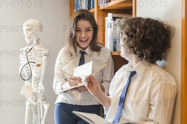 Laughing teenagers making notes library