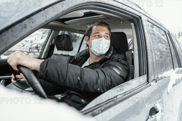 Man with medical mask driving car road trip