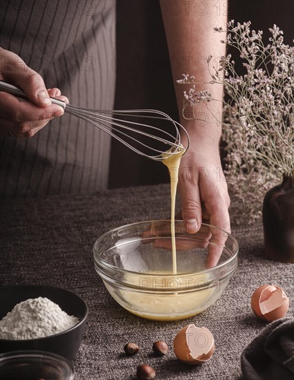 High angle cook whisking eggs bowl