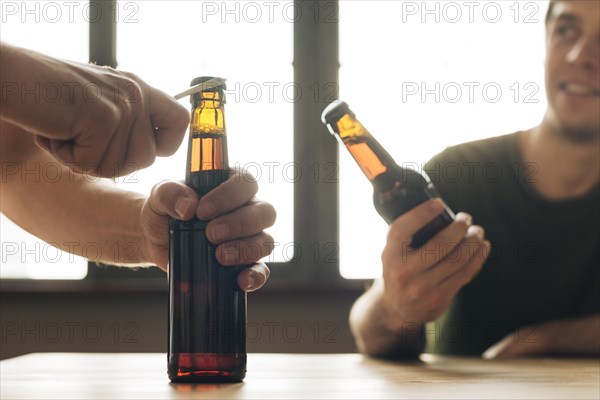 Man looking person opening brown beer bottle restaurant