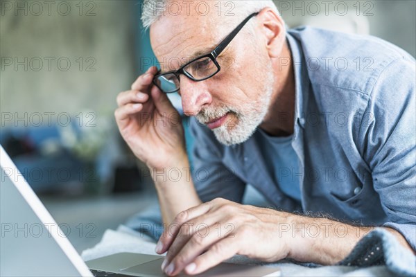 Senior man with hand eyeglasses looking laptop