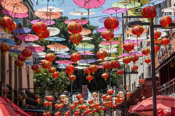 Red paper Chinese lanterns and umbrellas hanging above the street in Chinatown