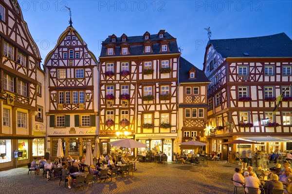 Gabled half-timbered houses on the busy medieval market square in the evening