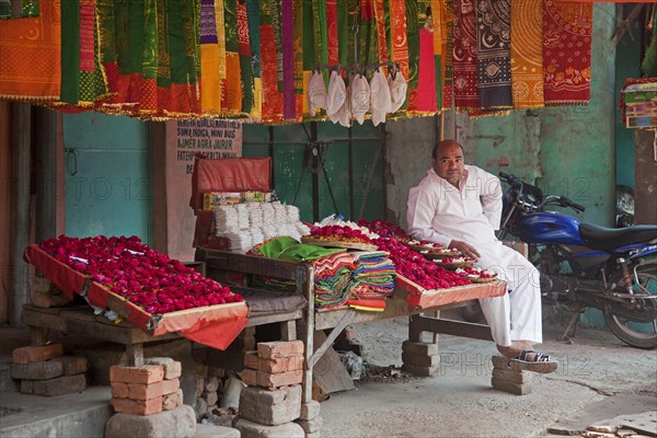 Vendor in front of shop selling scarfs and flowers as gifts for offerings near the Nizam-Ud-Din shrine in Delhi