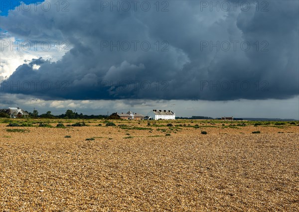 Dark rain clouds over houses and beach at Shingle Street