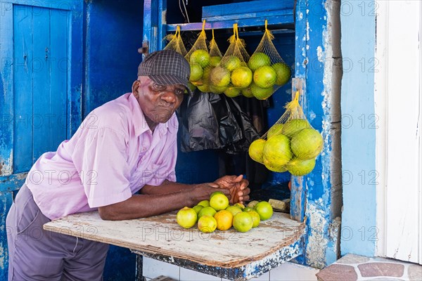 Old local black man selling oranges and lemons at market in the city Georgetown