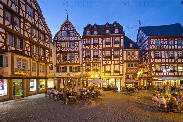 Gabled half-timbered houses on the busy medieval market square in the evening