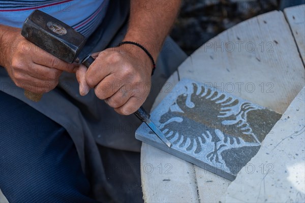 Albanian sculptor chopping making the country's coat of arms in the stone