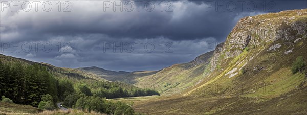 Mountain scenery showing dark rain clouds rolling in over sunny hillside and valley in Wester Ross