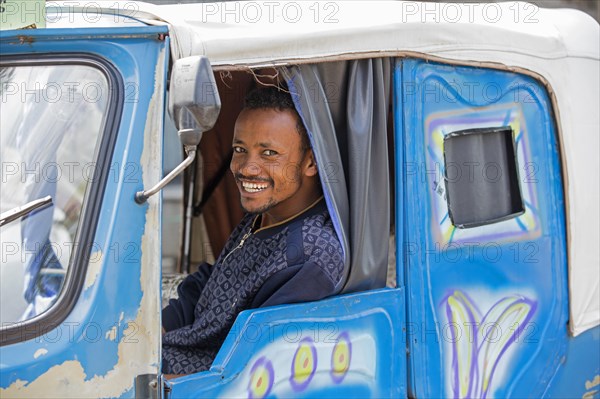 Black taxi driver smiling in tuk-tuk