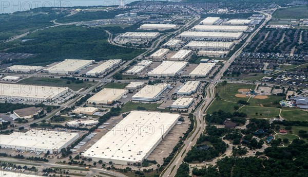 Oblique angle aerial view of large distribution centre logistics warehouse buildings on landing approach to Fort Worth