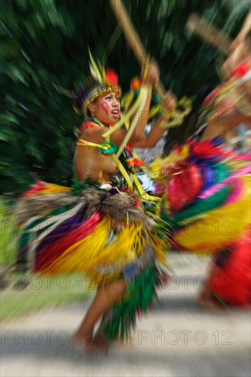 Dancer from Yap Island in traditional historical dress with headdress performs ritual bamboo dance with bamboo stick