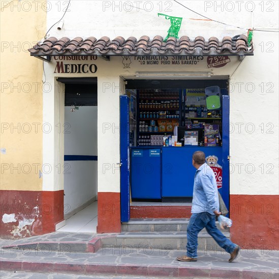 Man walking past small pharmacy shop