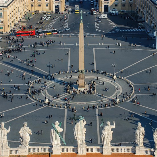 Bird's eye view of ancient Egyptian Vatican Rose granite obelisk in St Peter's Square in foreground sculptures statues of saints on roof main portal portal of St Peter's Basilica