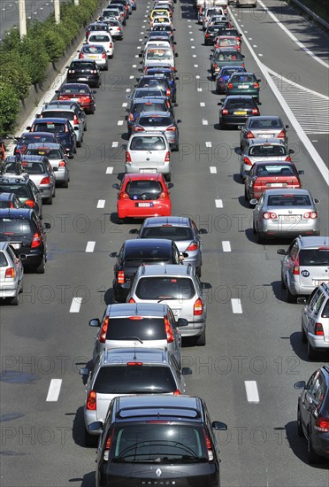 Cars queueing in highway lanes at approach slip road during traffic jam on motorway during summer holidays