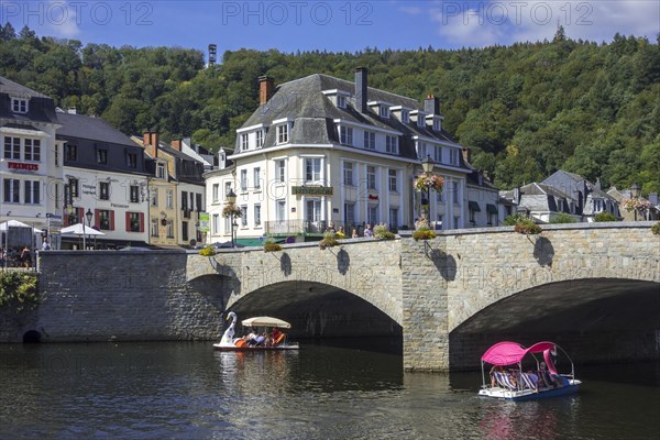 Paddle boats with tourists passing under the bridge Pont de Liege in the city Bouillon in summer