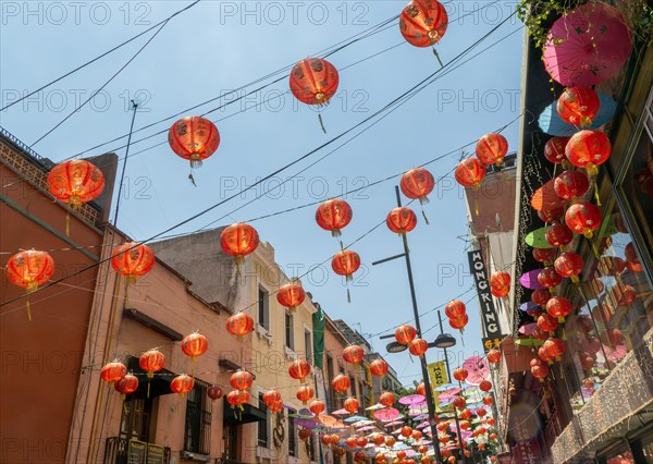 Red paper Chinese lanterns and umbrellas hanging above the street in Chinatown