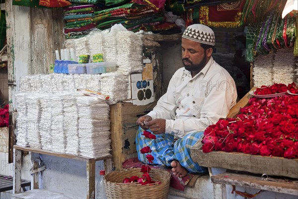 Vendor in front of shop selling scarfs and flowers as gifts for offerings near the Nizam-Ud-Din shrine in Delhi