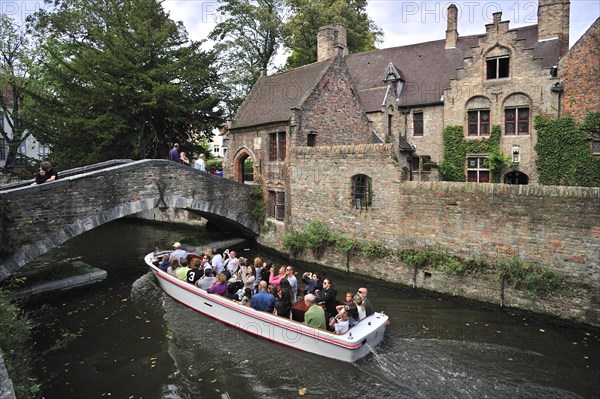 Bonifacius bridge over canal and tourists during sightseeing boat trip in Bruges