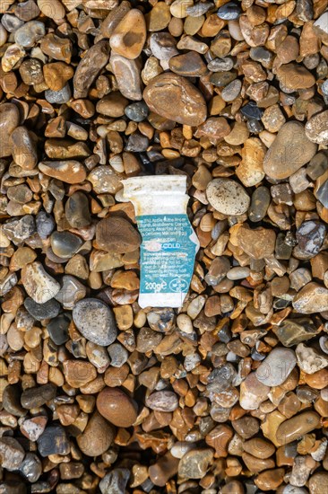 Fragment of polystyrene food package washed up on shingle beach